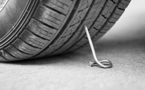 nail on an asphalt road with a car